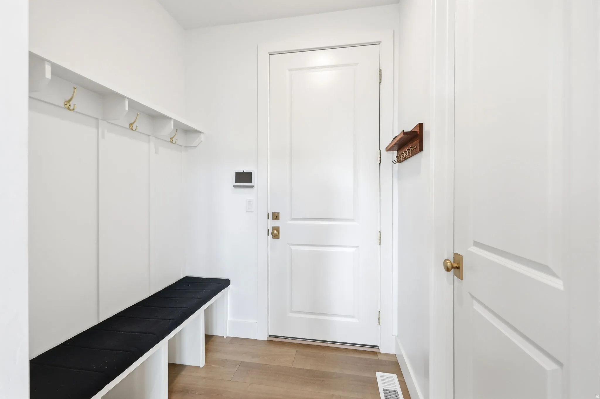 Foyer with built-in bench seating, storage shelf, and brass coat hooks