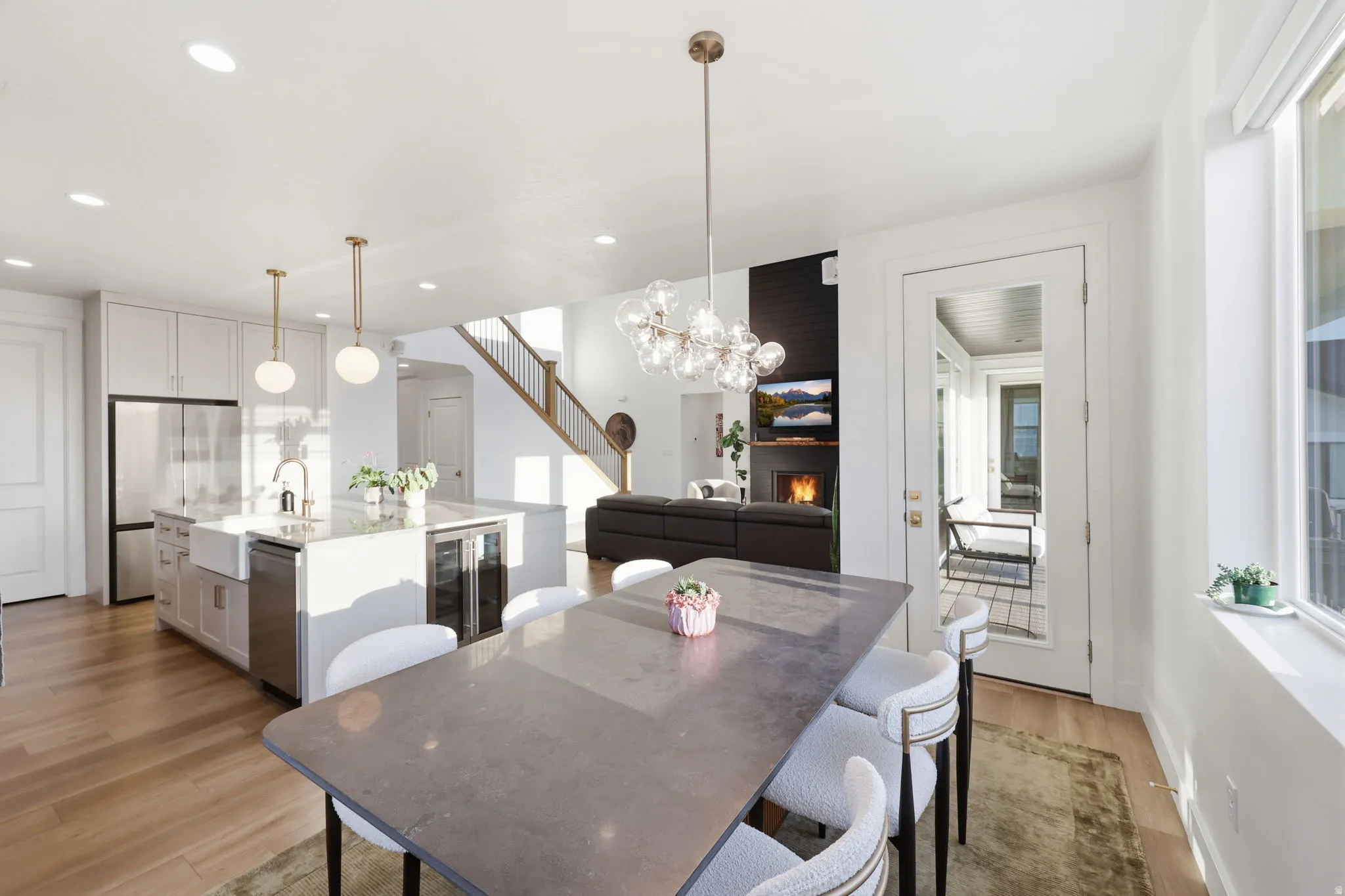 Open-concept kitchen and dining area featuring a large island with waterfall-edge countertop, pendant lighting, and stainless steel appliances