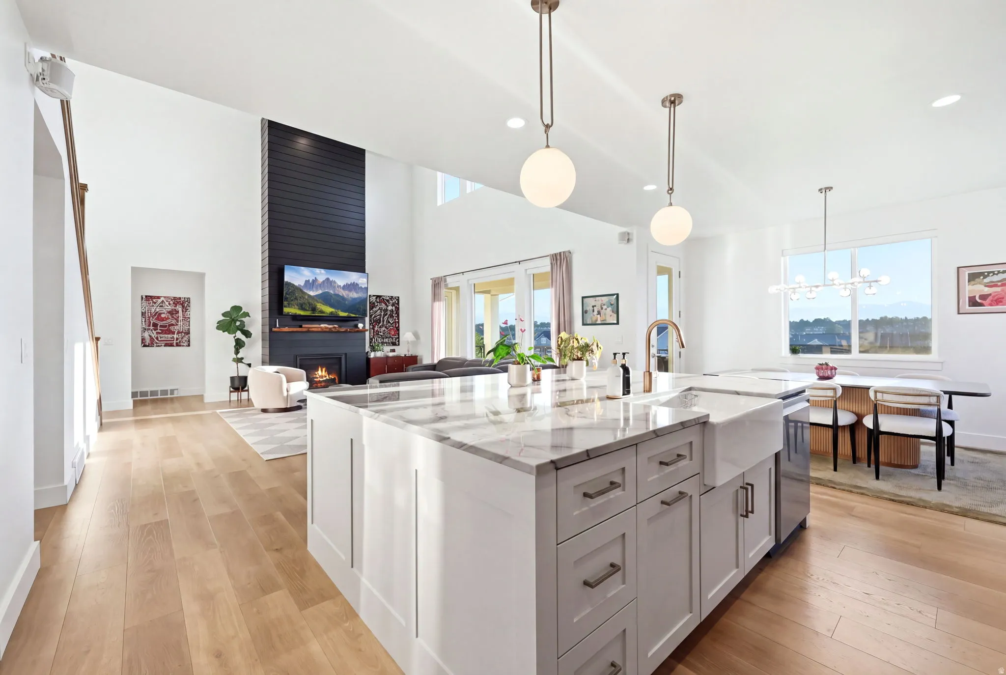 Modern open-concept kitchen and great room featuring a large center island with gray cabinetry and stainless steel hardware, white perimeter cabinetry, and quartz countertops