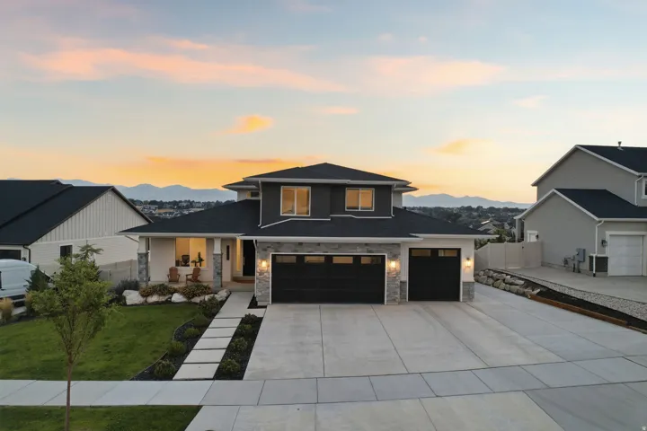 Contemporary residence featuring a two-car garage, stone and siding facade, and a covered front porch