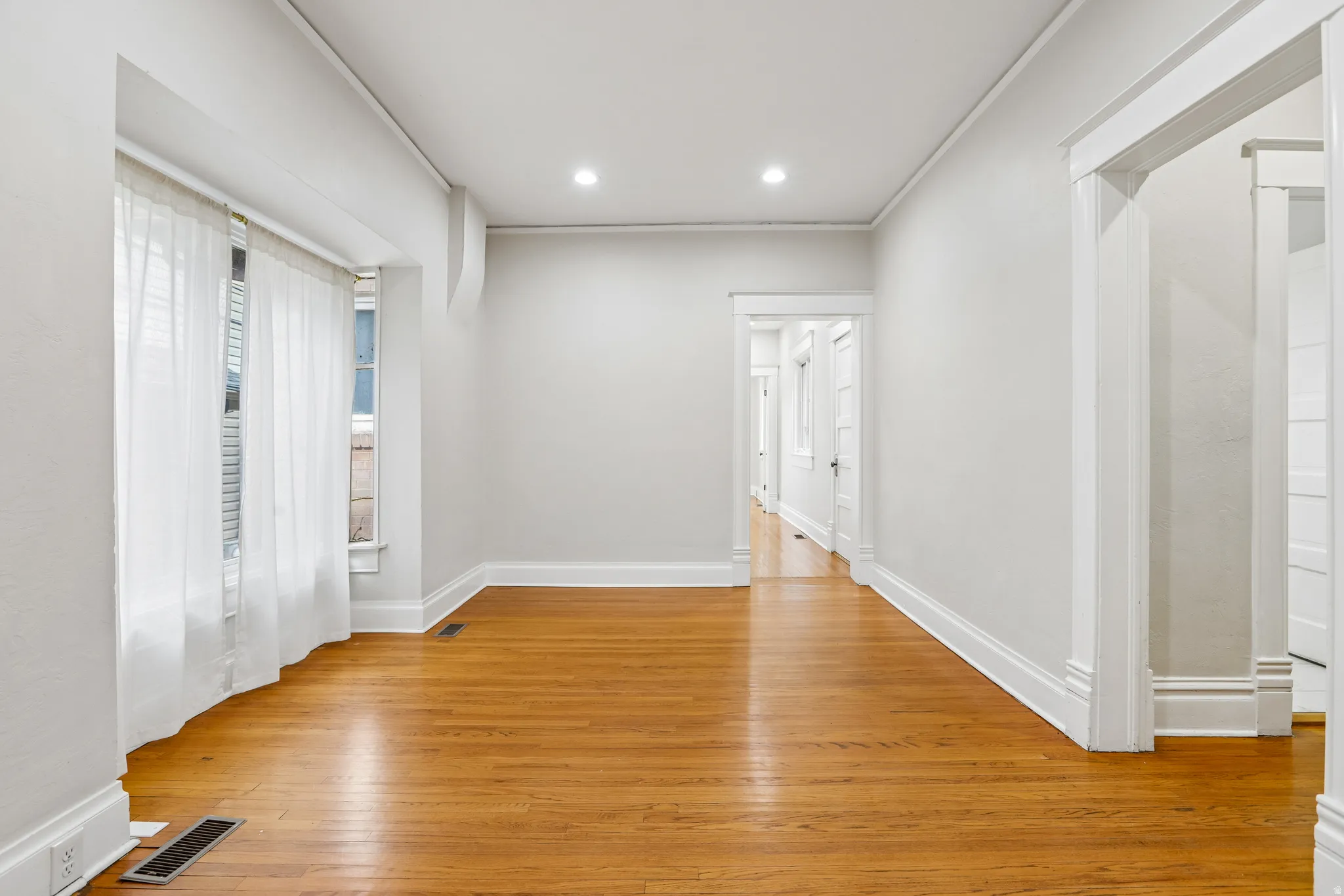 Spacious room featuring wood-finish flooring, recessed lighting, and bright white walls