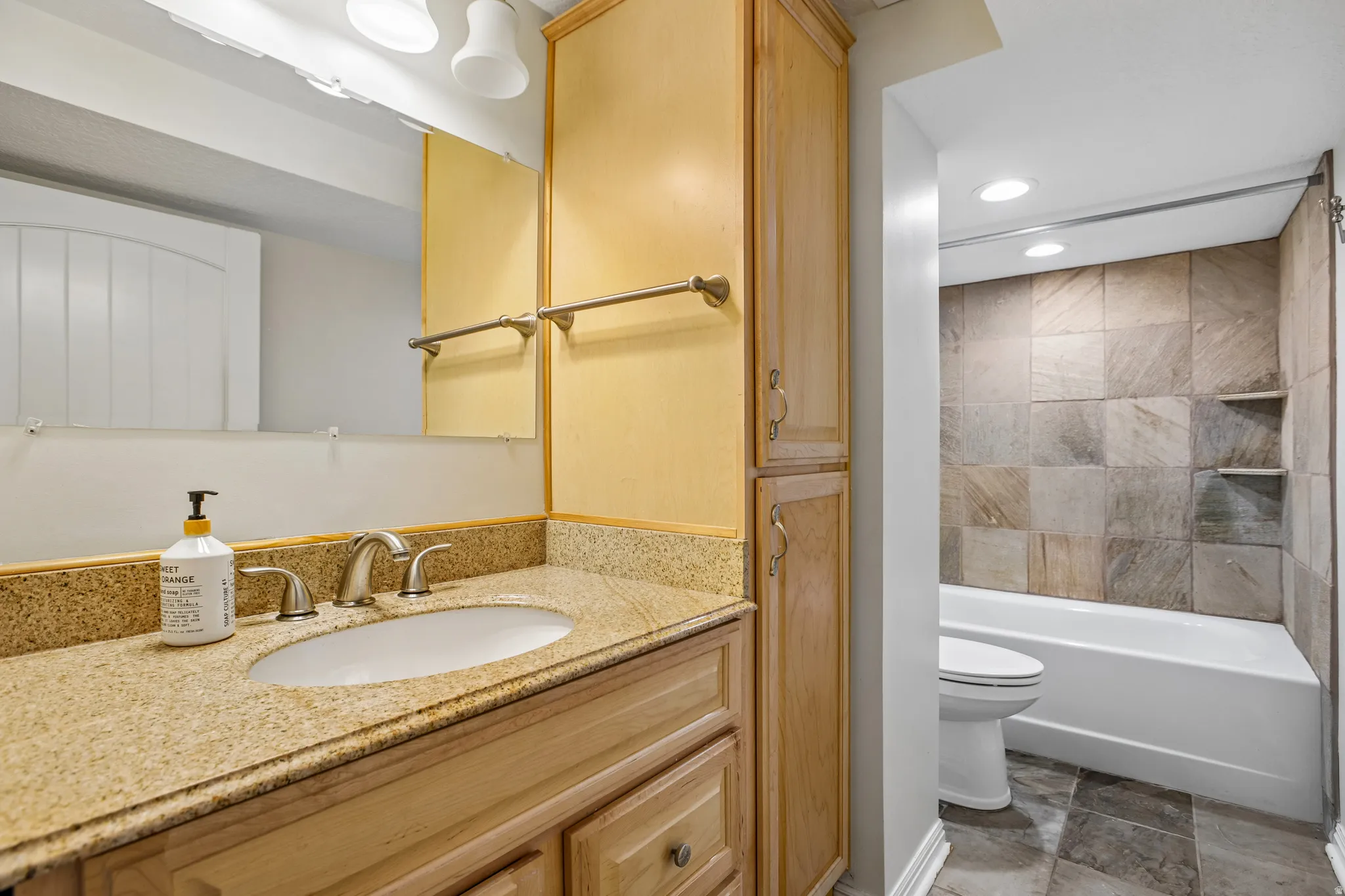 Bathroom vanity featuring a light-toned stone countertop with an undermount sink and brushed nickel faucet