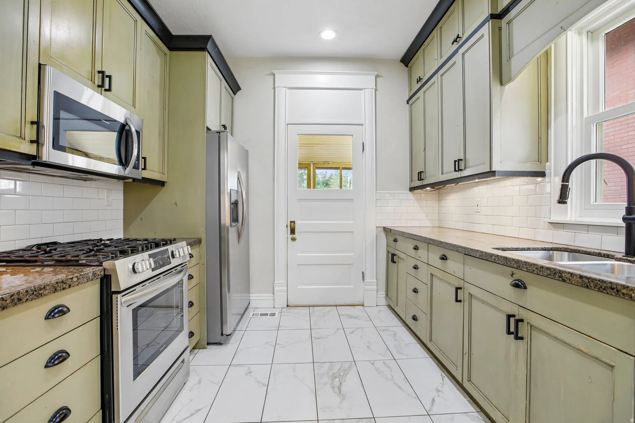 Galley kitchen featuring light-toned cabinetry with dark hardware and crown molding