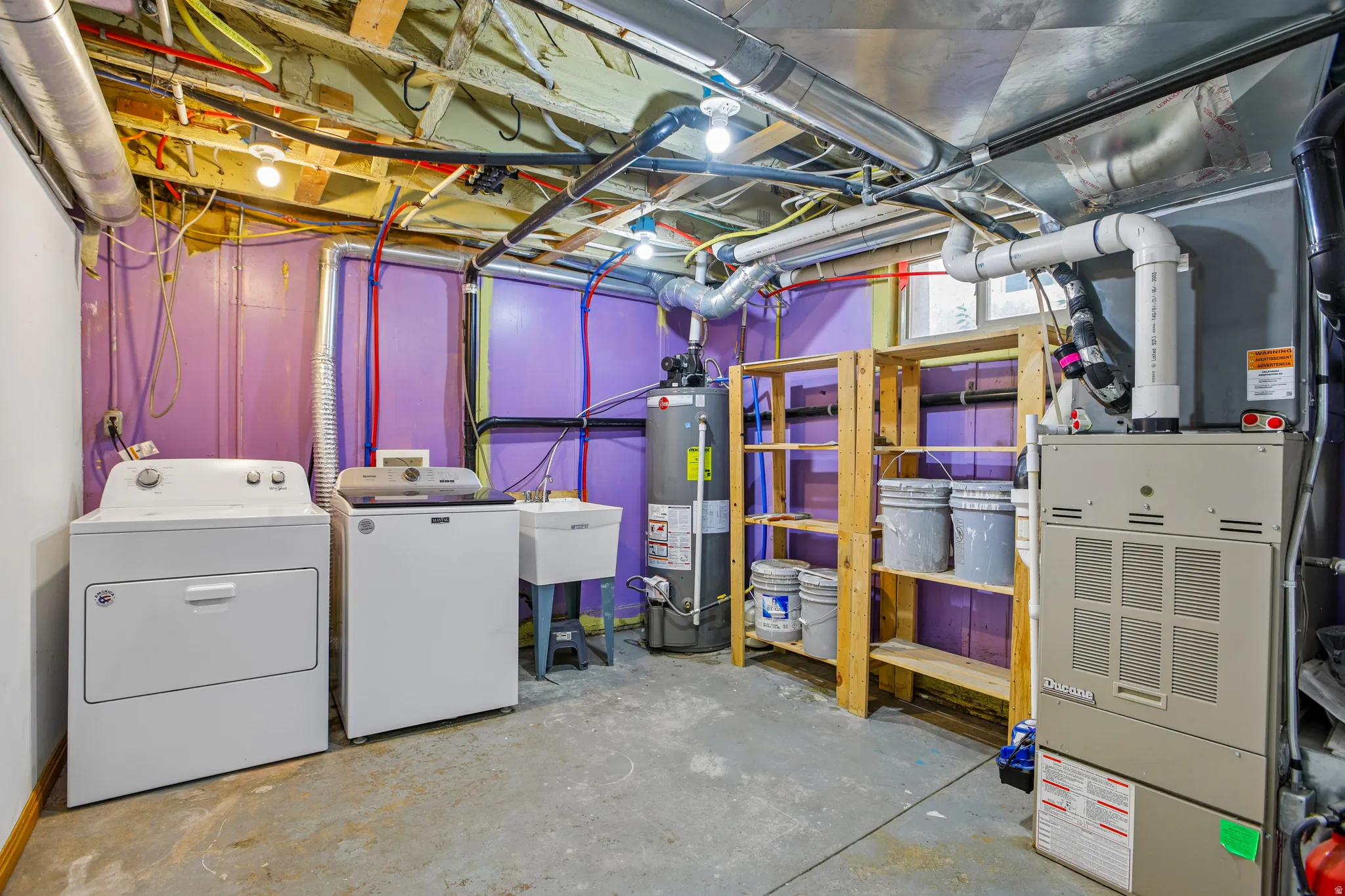 Dedicated utility space featuring laundry appliances, a utility sink, and exposed overhead ductwork