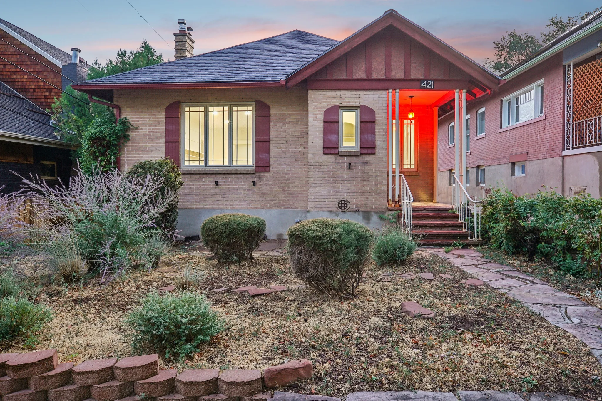 Brick exterior with a covered front porch, red accent trim, and a stone walkway