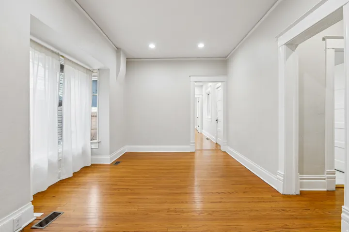 Spacious room featuring wood-finish flooring, recessed lighting, and bright white walls