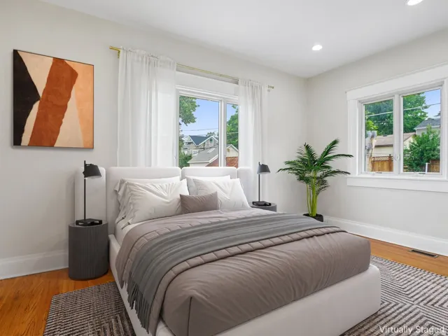 Bedroom featuring rich wood-finish flooring, recessed lighting, and multiple windows with white trim