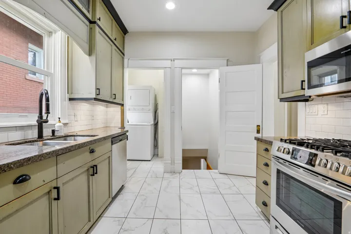 Kitchen featuring wood-finish cabinetry with dark hardware, granite countertops, and a subway tile backsplash