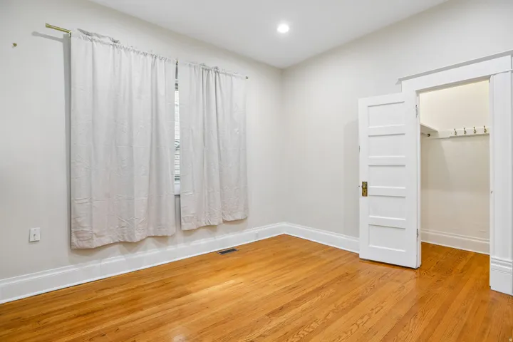 Room featuring wood-finish flooring, recessed lighting, and a window with a curtain rod