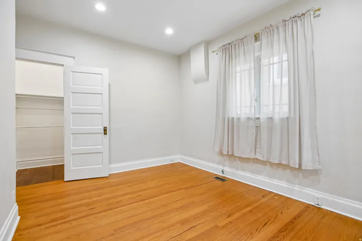 Hardwood flooring throughout featuring recessed lighting, a closet with built-in shelving, a large window, and white trim
