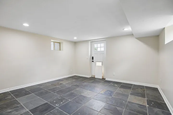 Substantial room featuring large format slate floor tiles, recessed lighting, neutral wall tones, and a paneled exterior door with glass lites