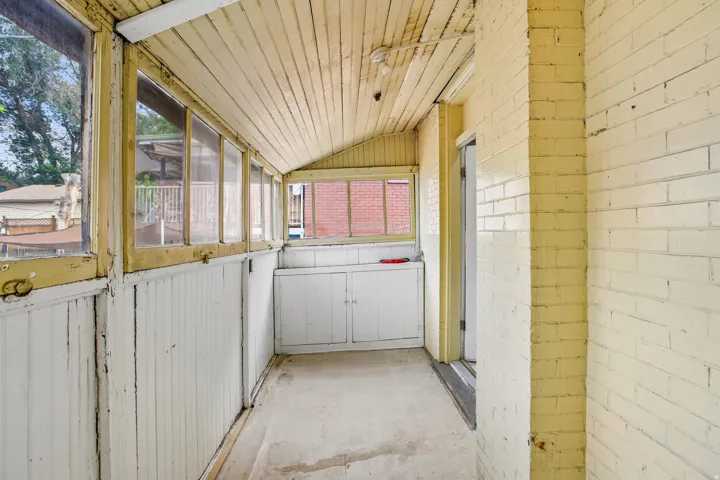 Enclosed porch featuring multiple windows, a wood-finish slatted ceiling, and beadboard paneling