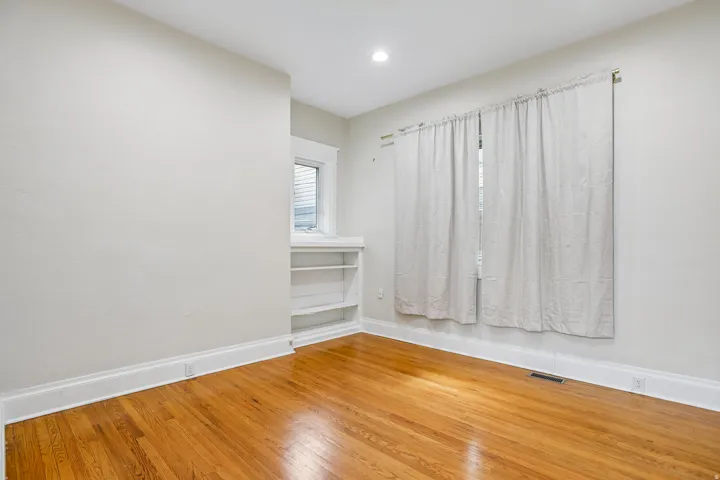 Room with wood-finish flooring, light-colored walls, and a recessed ceiling light