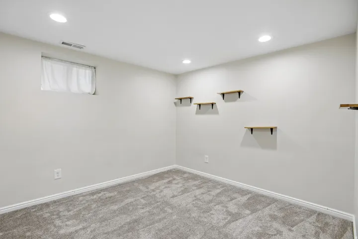 Neutral-toned carpeting complements light gray wall finishes in this room, featuring recessed ceiling lighting