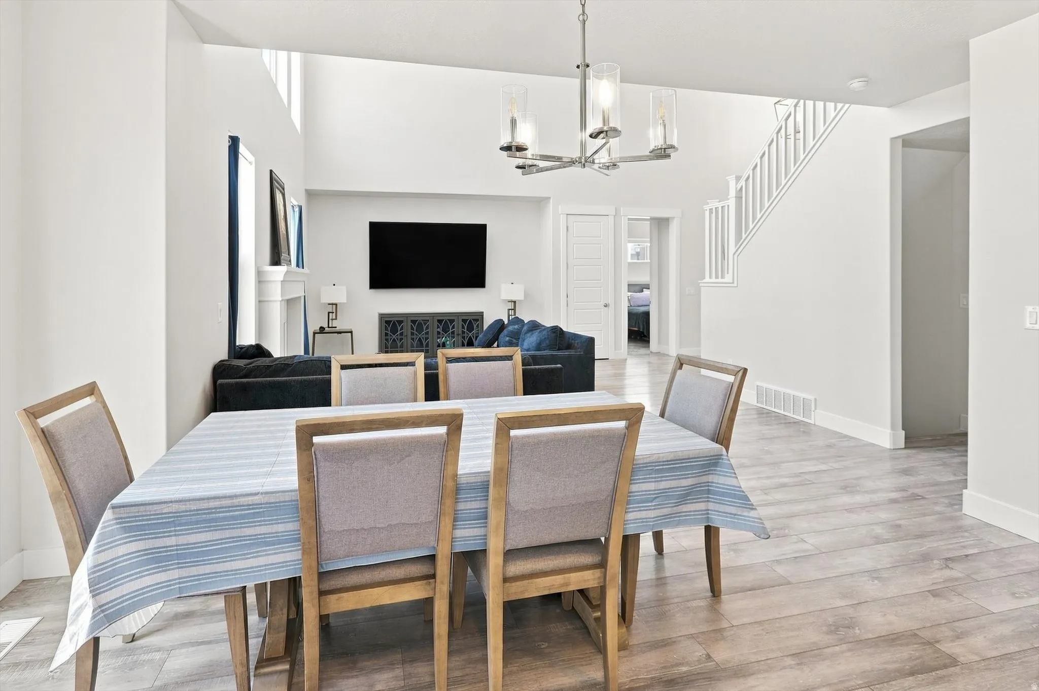 Open-concept living area featuring a wood-finish plank floor, dining table seating for four, pendant lighting, and entertainment built-ins with display cabinetry