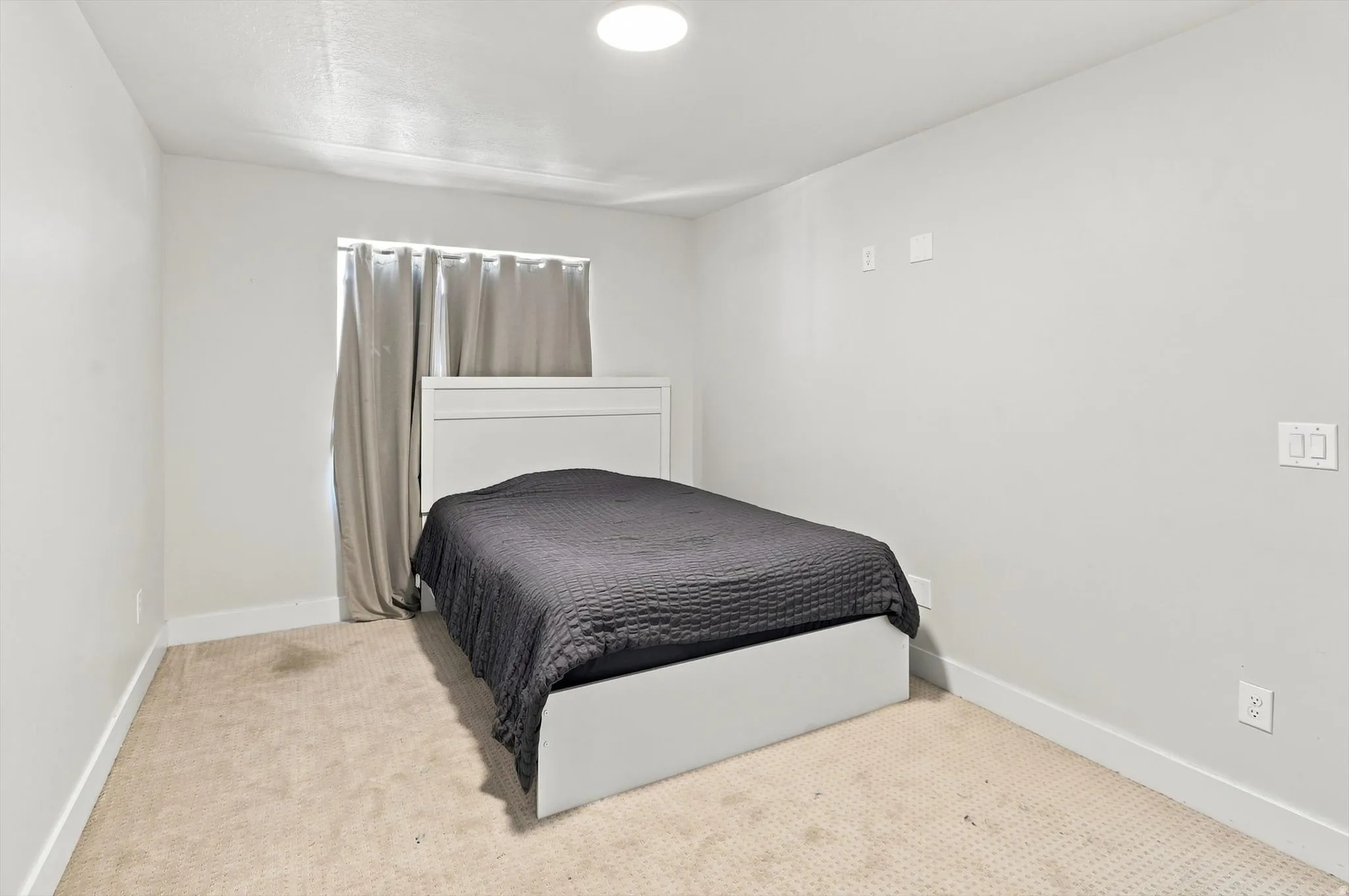 Bedroom featuring neutral wall finishes, recessed ceiling lighting, carpeted flooring, and a white built-in headboard with storage