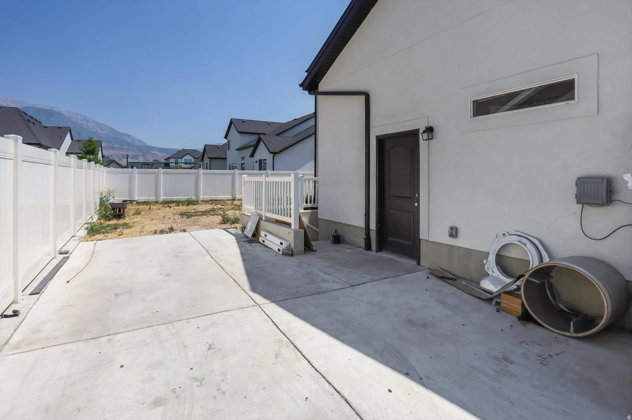 Concrete patio with a white vinyl privacy fence and an exterior door
