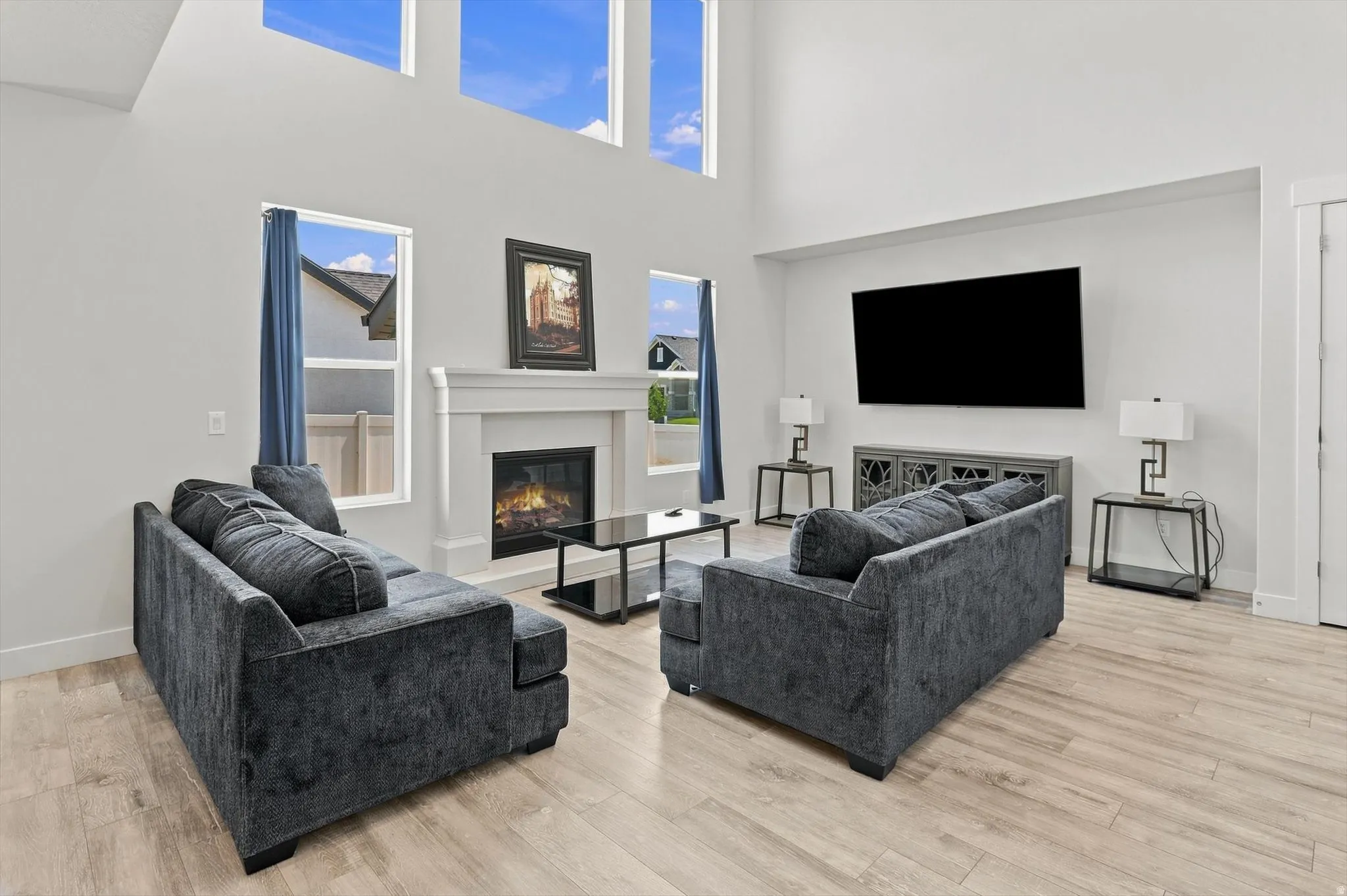 Double-height ceilings, wood-finish flooring, and a built-in fireplace with a mantel