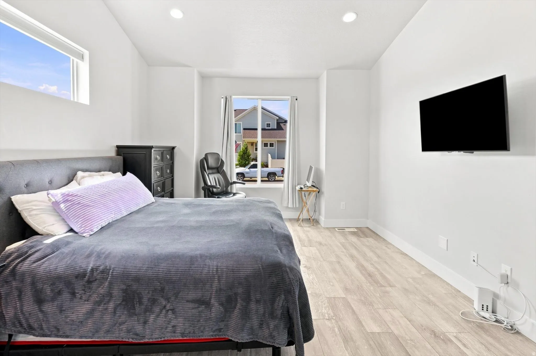 Recessed lighting, light wood-finish flooring, white walls, and a large window