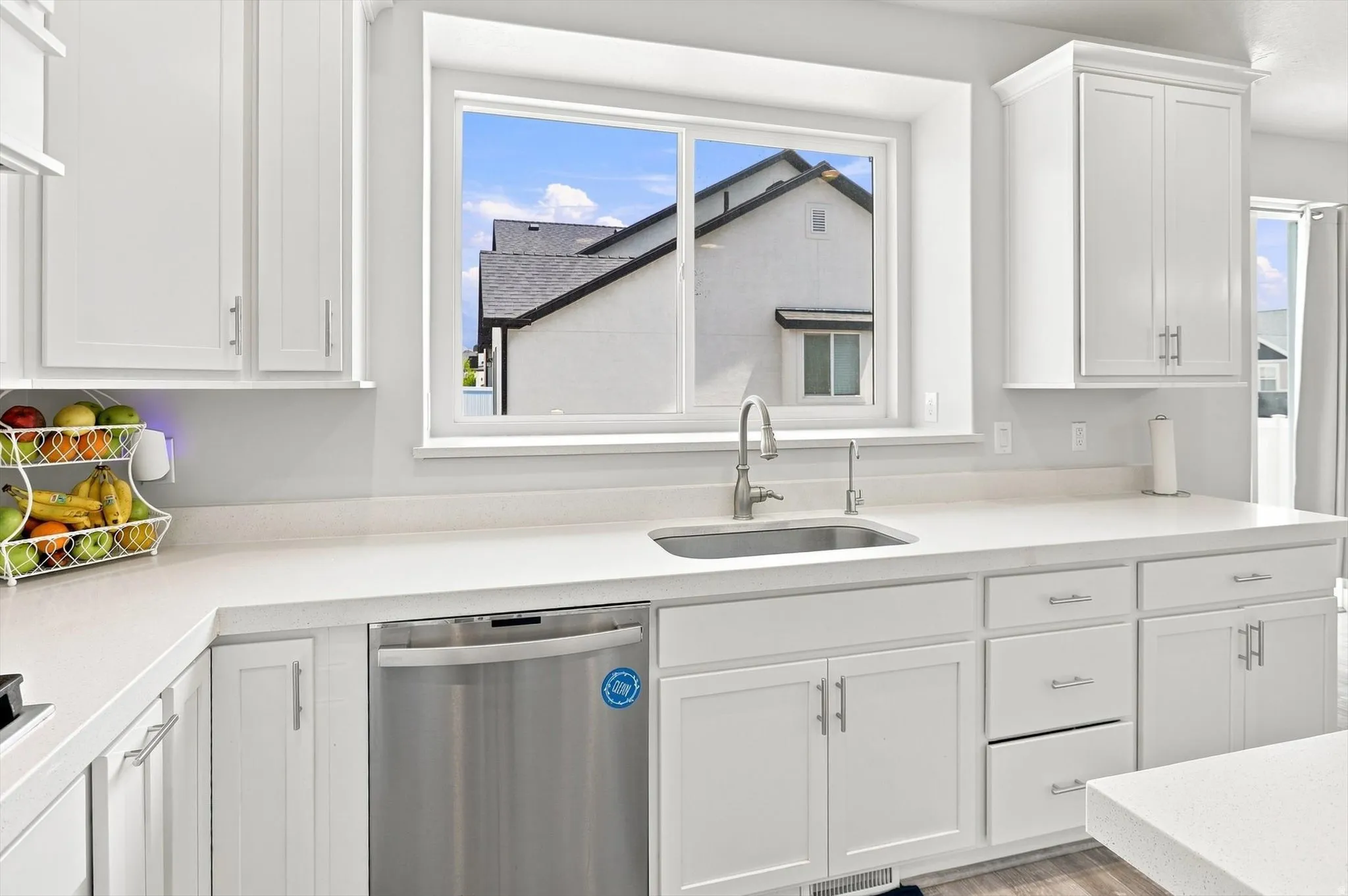 Bright, updated kitchen featuring white shaker-style cabinetry, stainless steel appliances, and a large window framing natural light