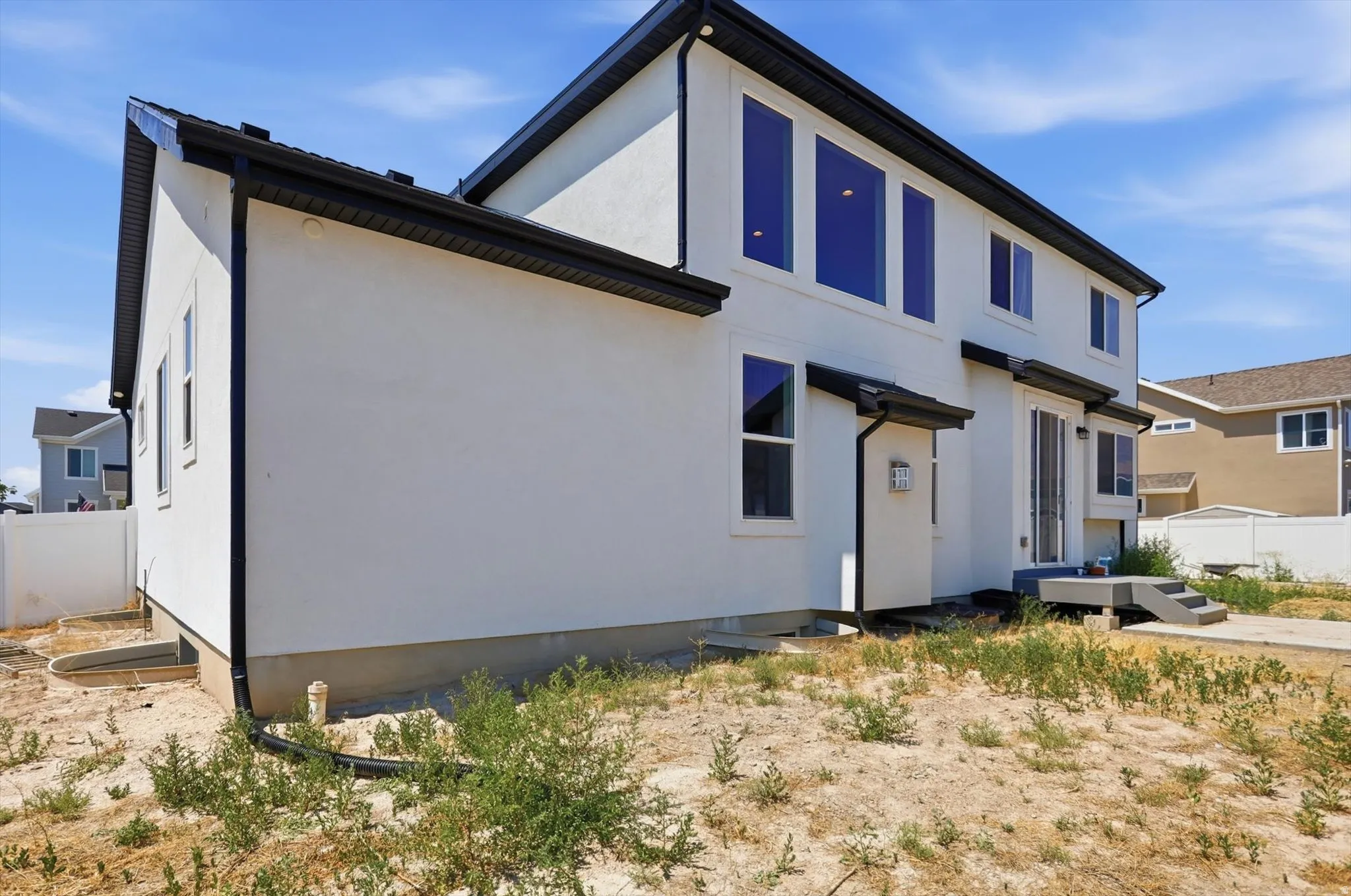 Modern two-story residence featuring a clean white exterior with contrasting dark trim, multiple blue-framed windows, and a covered front entry