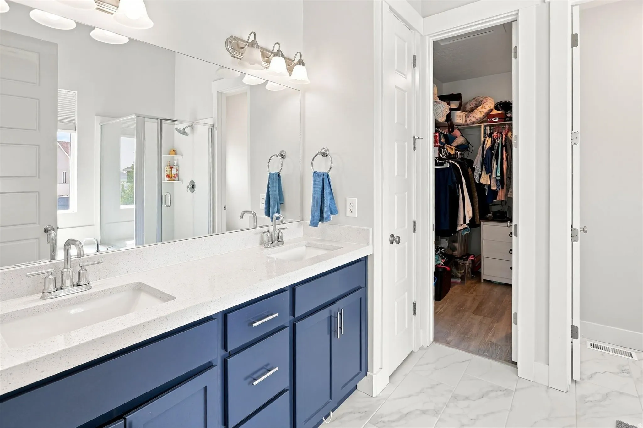Dual sink vanity with blue cabinetry, white countertop, and chrome fixtures
