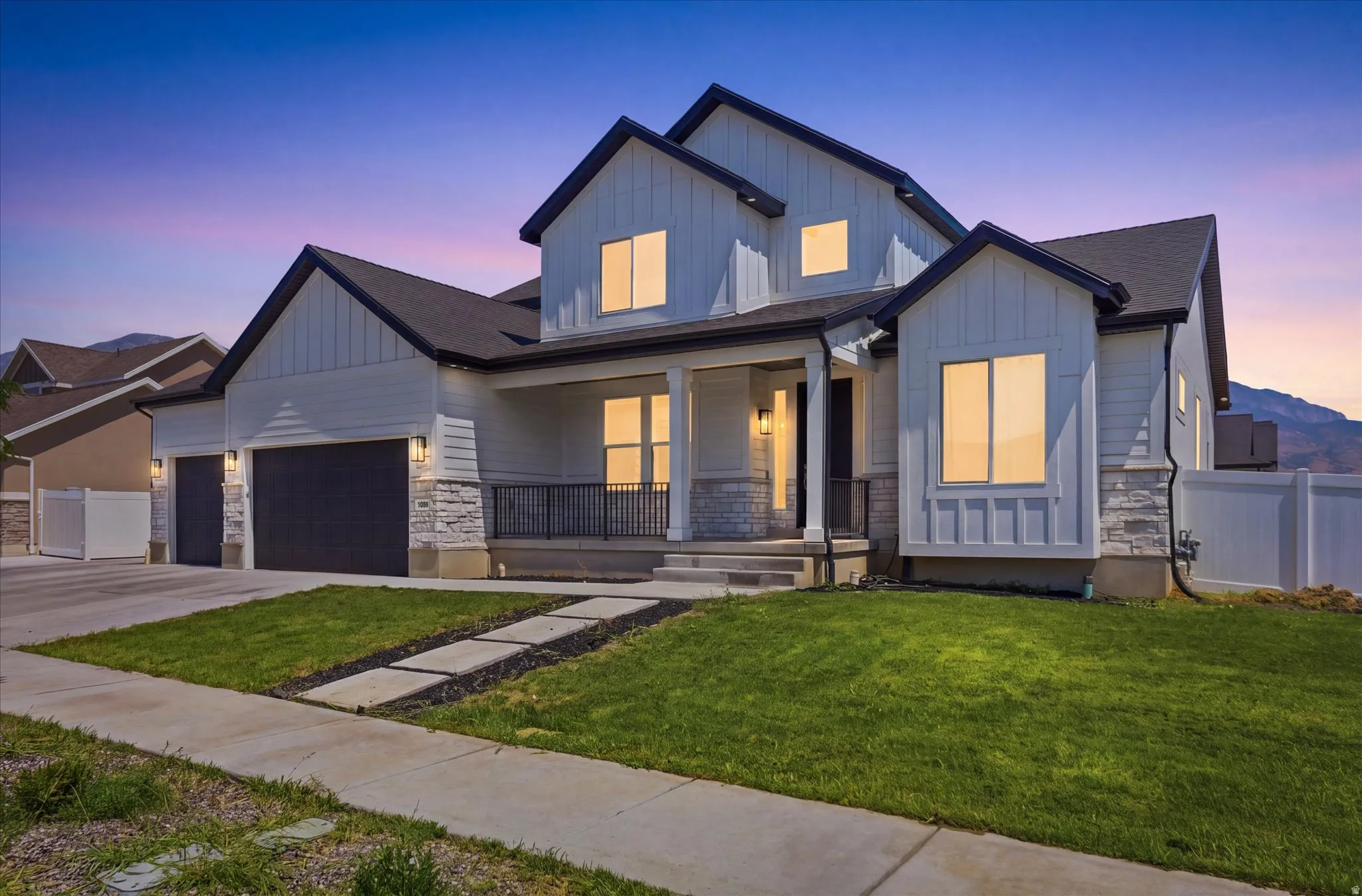 Modern two-story residence featuring a distinctive peaked roofline with multiple gables, board-and-batten siding in gray tones, and stone accents at the foundation