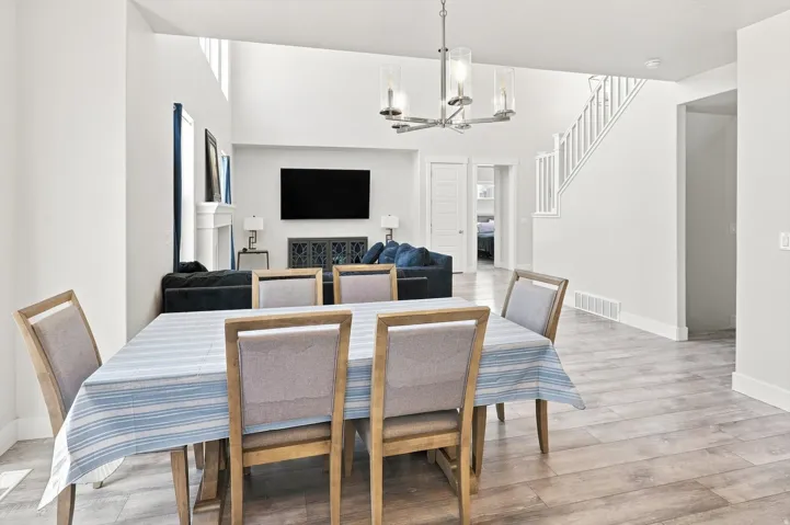 Open-concept living area featuring a wood-finish plank floor, dining table seating for four, pendant lighting, and entertainment built-ins with display cabinetry