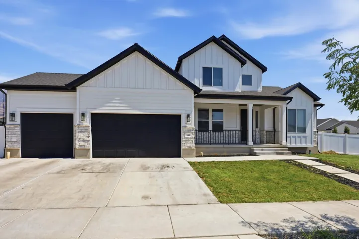 Modern farmhouse-style exterior featuring white siding, black trim, a covered porch with white columns, and a two-car garage with dark doors