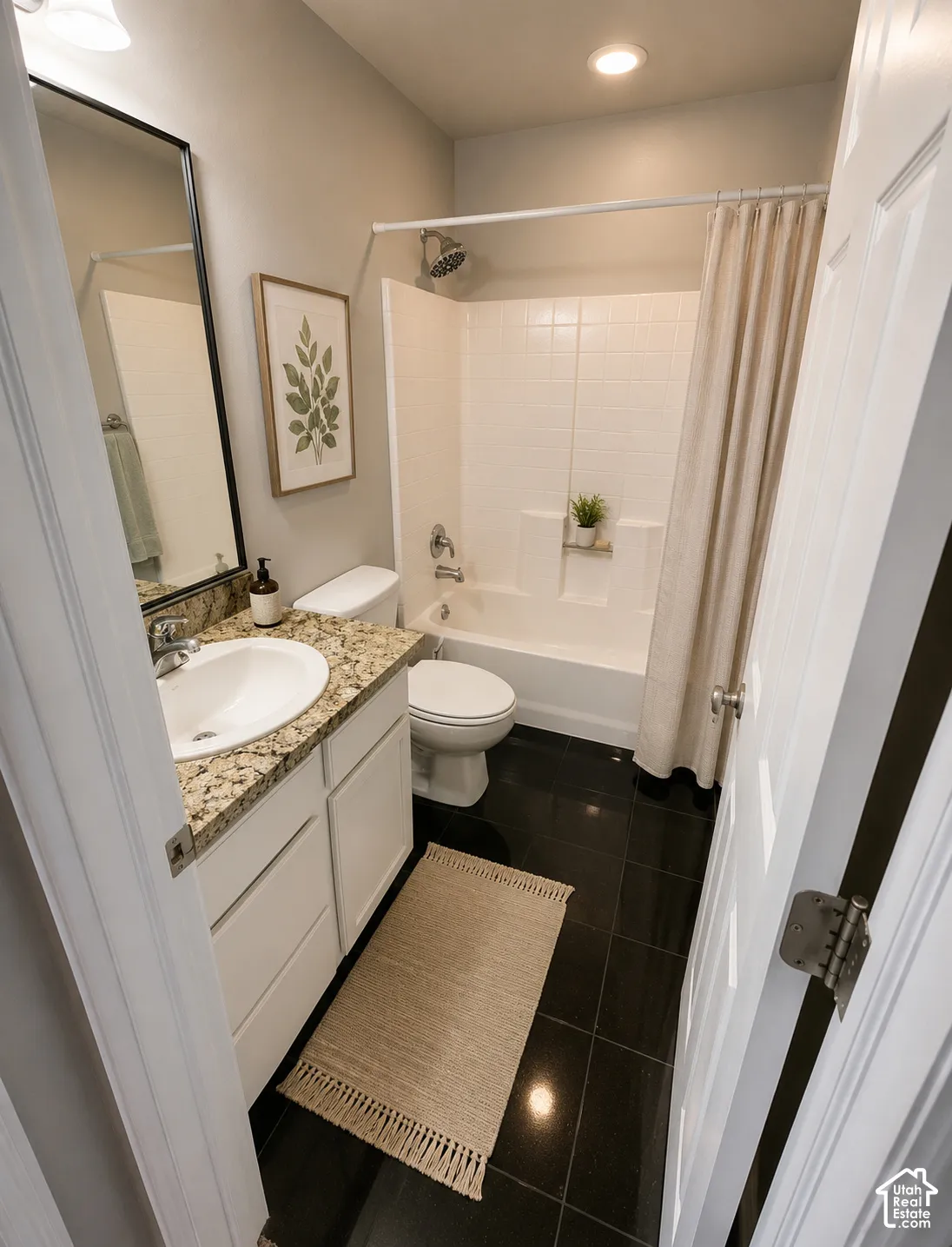 Modern bathroom featuring a white vanity with a round vessel sink and granite-look countertop, chrome faucet, and matching framed mirror