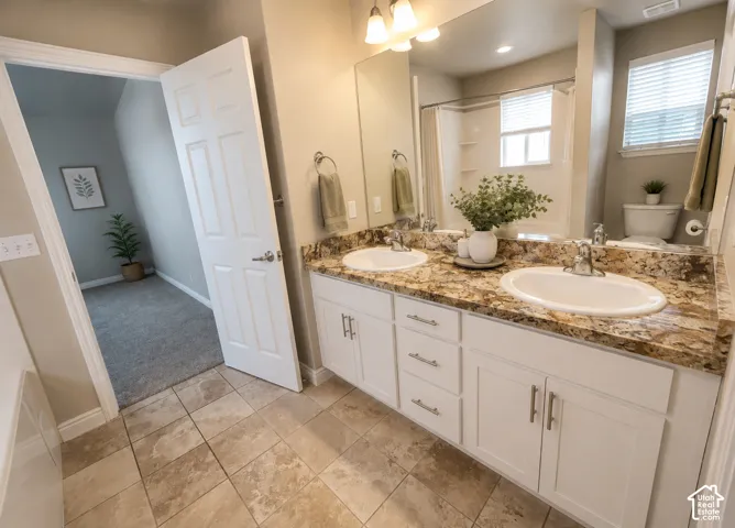 Double vanity with a granite countertop, dual undermount sinks, and white cabinetry