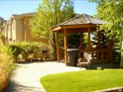 Mature landscaping and lush lawn create a serene outdoor retreat, anchored by a wood-frame gazebo with a pitched roof
