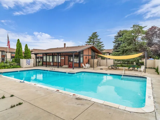 Outdoor swimming pool featuring integrated steps, concrete surround, and a perimeter fence