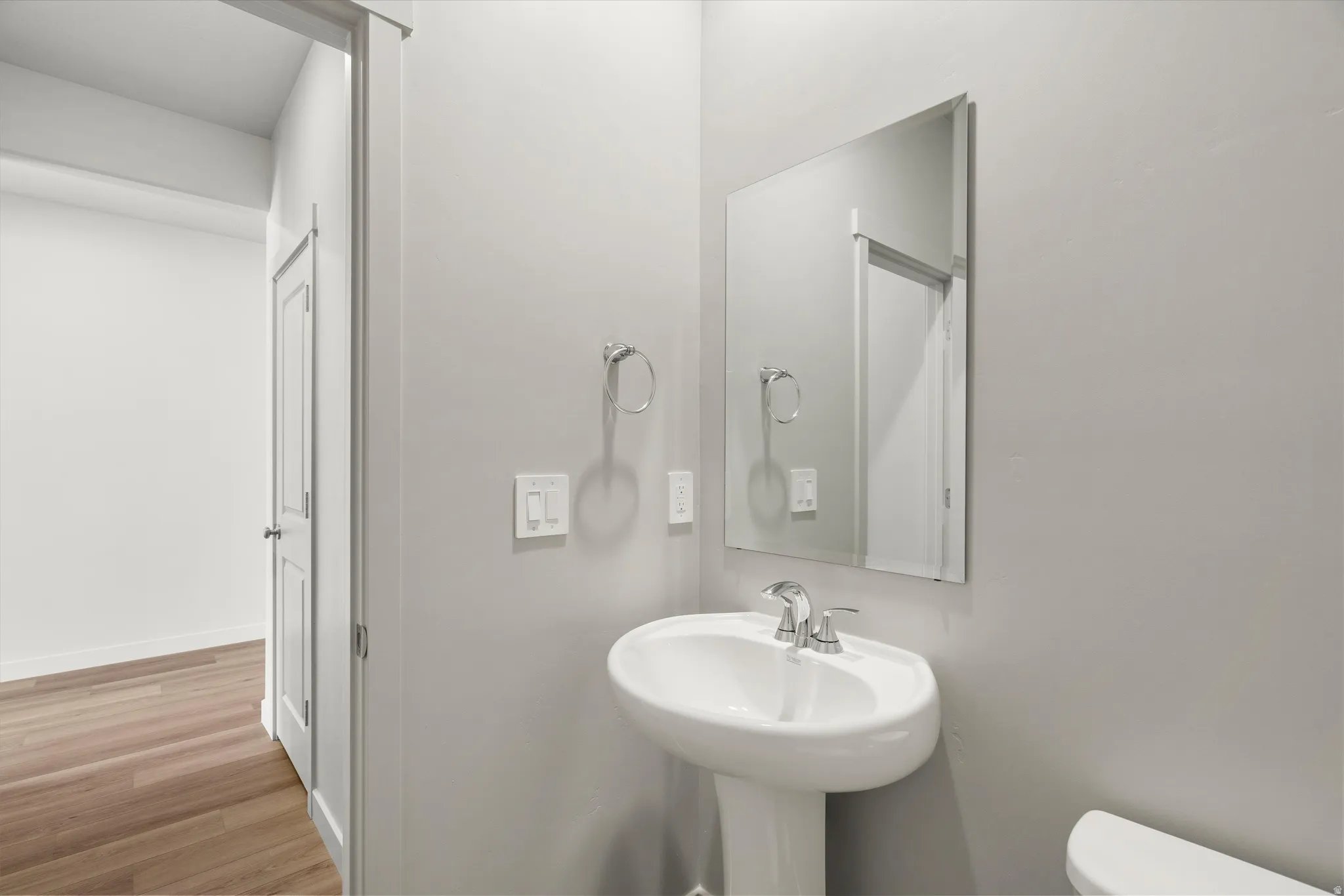 **DISCLAIMER** Interior package may vary. Pedestal sink with chrome faucet, wall-mounted mirror, and wood-finish flooring