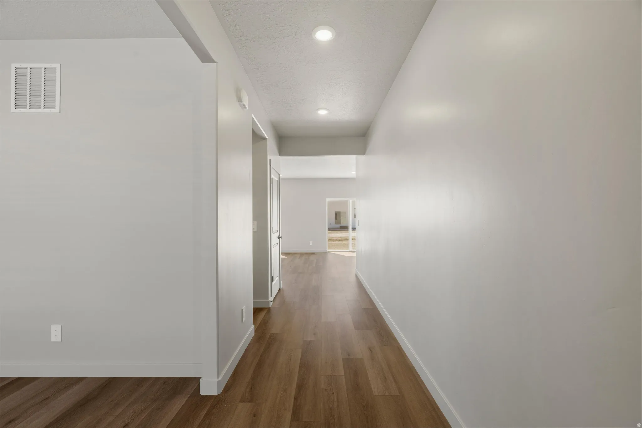**DISCLAIMER** Interior package may vary. Hallway featuring wood-finish flooring, recessed lighting, and neutral wall tones