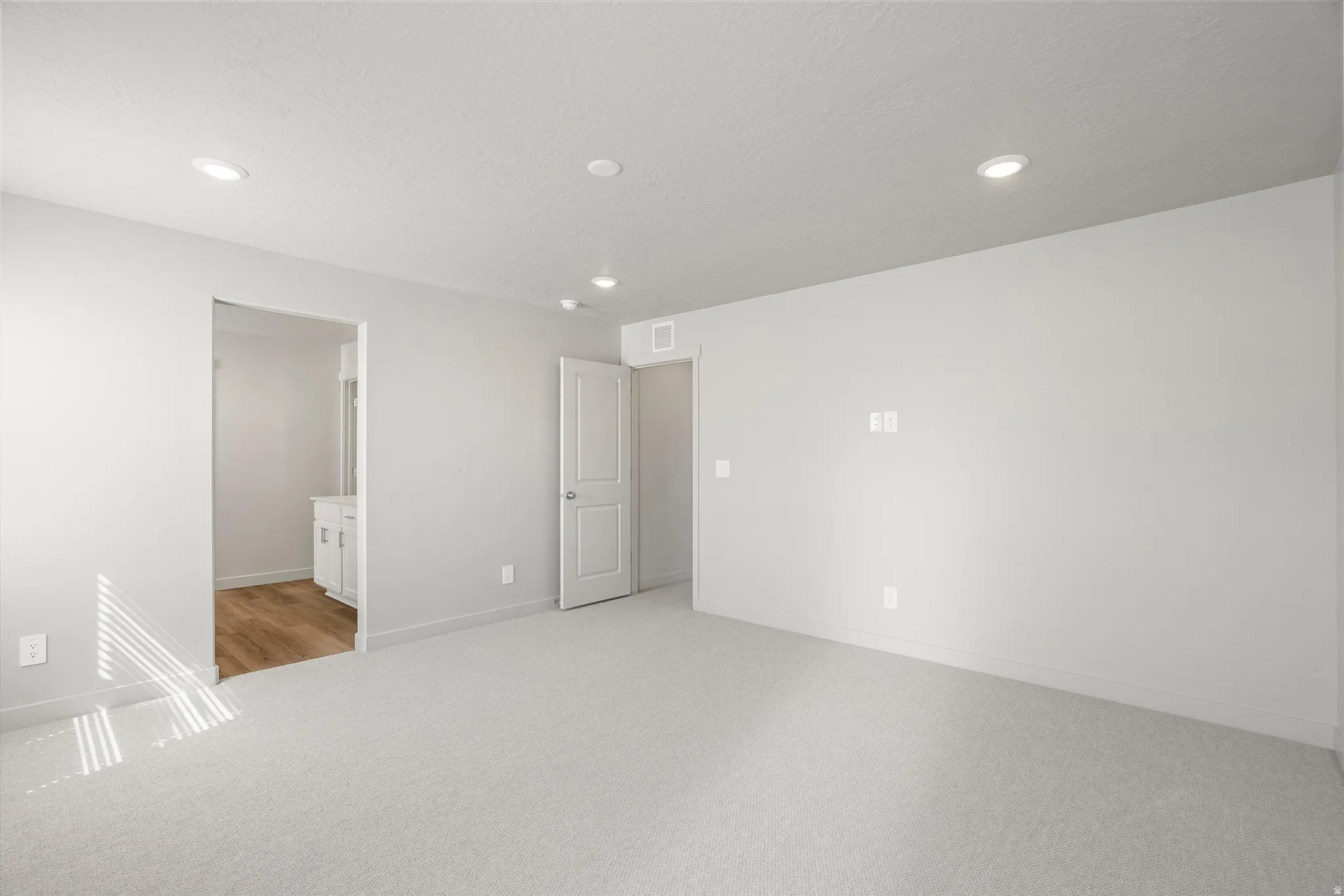 **DISCLAIMER** Interior package may vary. Bright, open bedroom featuring recessed ceiling lighting, multiple closet spaces with white panel doors, and neutral carpet flooring