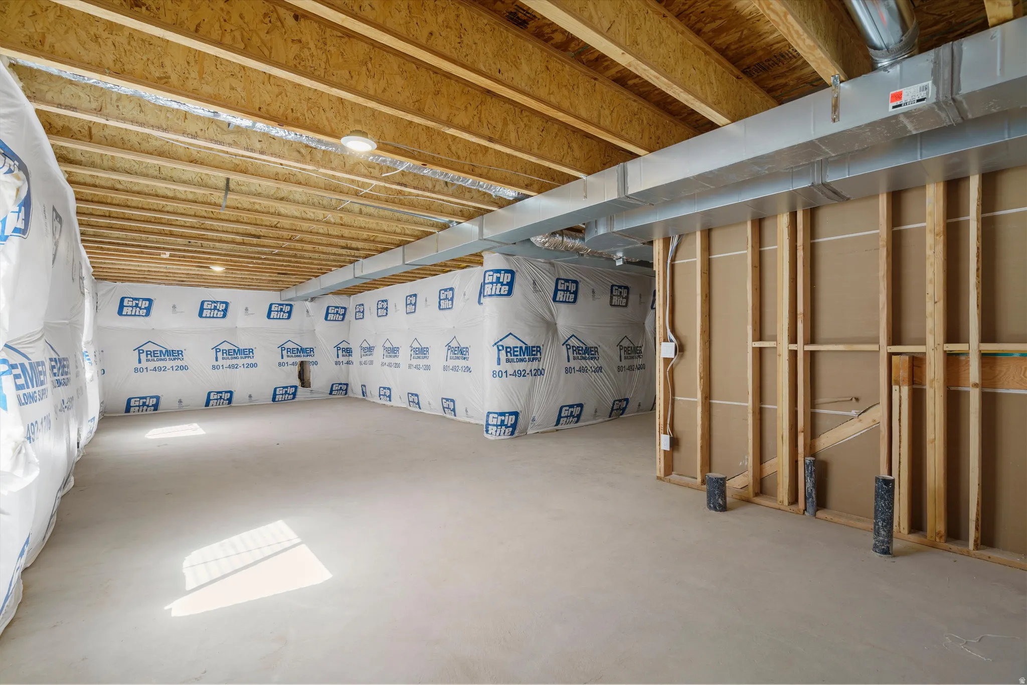 Unfinished basement with exposed ceiling joists, concrete flooring, and partial wall framing