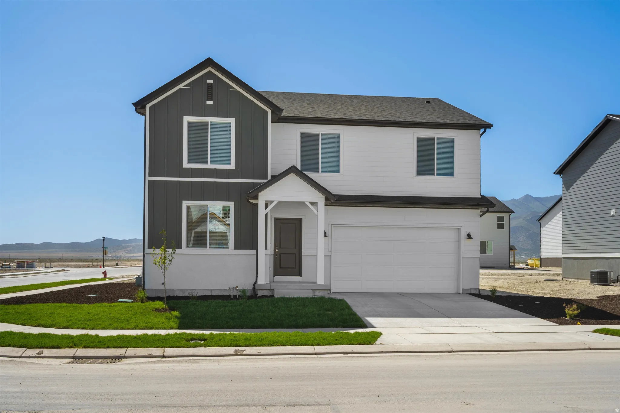 Two-story residence featuring a covered entry, attached two-car garage, and a combination of horizontal siding and vertical board and batten siding