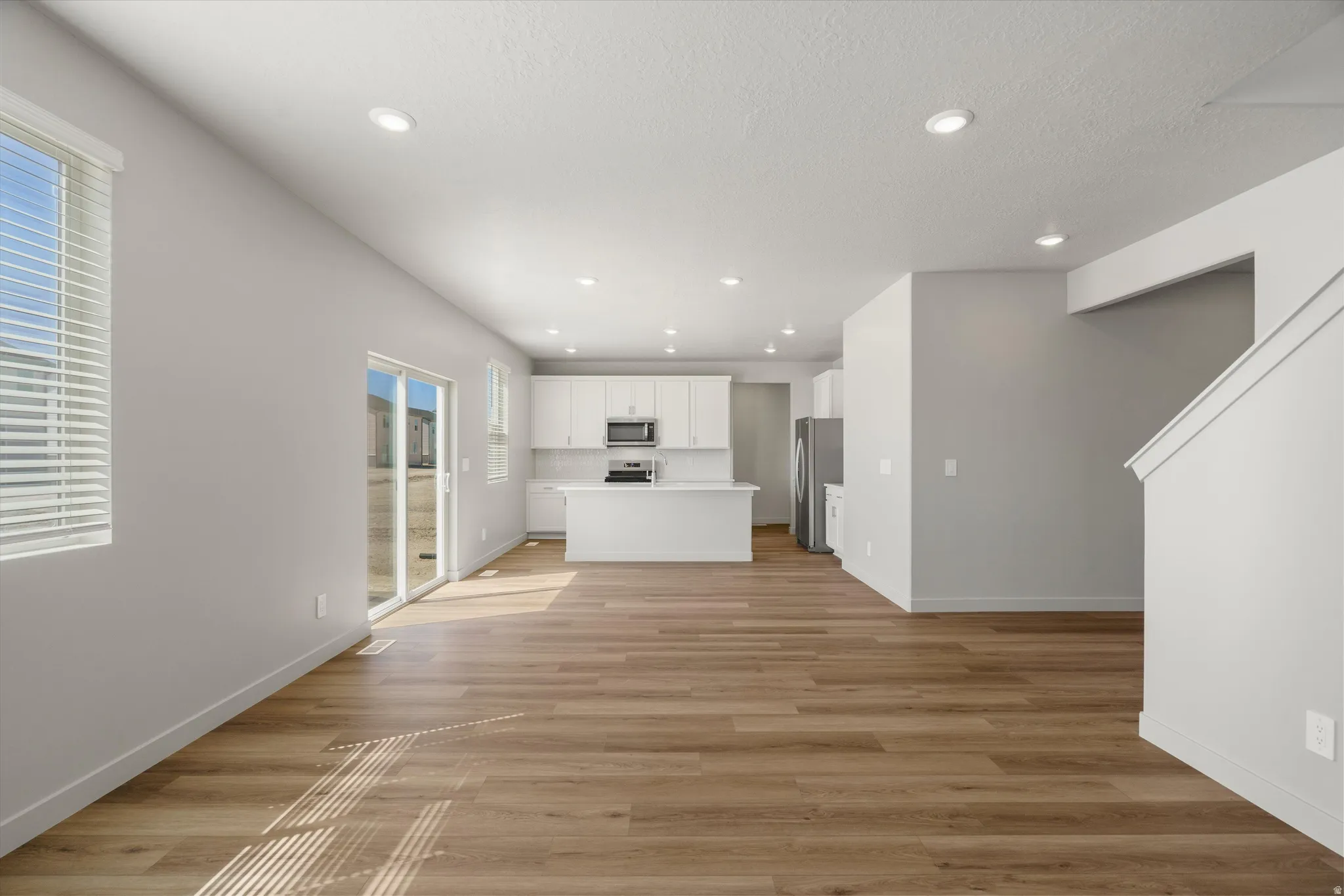 **DISCLAIMER** Interior package may vary. Open-concept living area with wood-finish flooring, recessed lighting, and sliding glass door