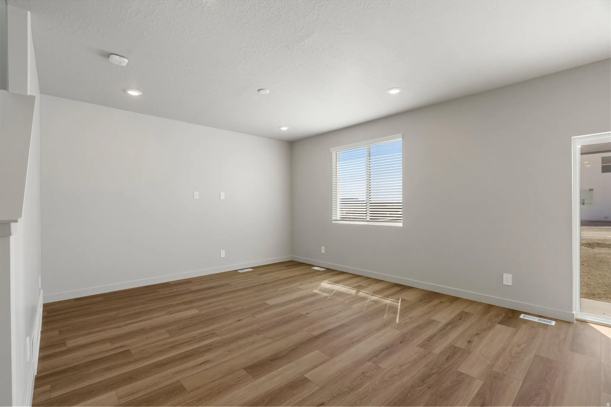 **DISCLAIMER** Interior package may vary. Bright, open room featuring wood-finish flooring, recessed ceiling lighting, and large windows with plantation shutters allowing abundant natural light