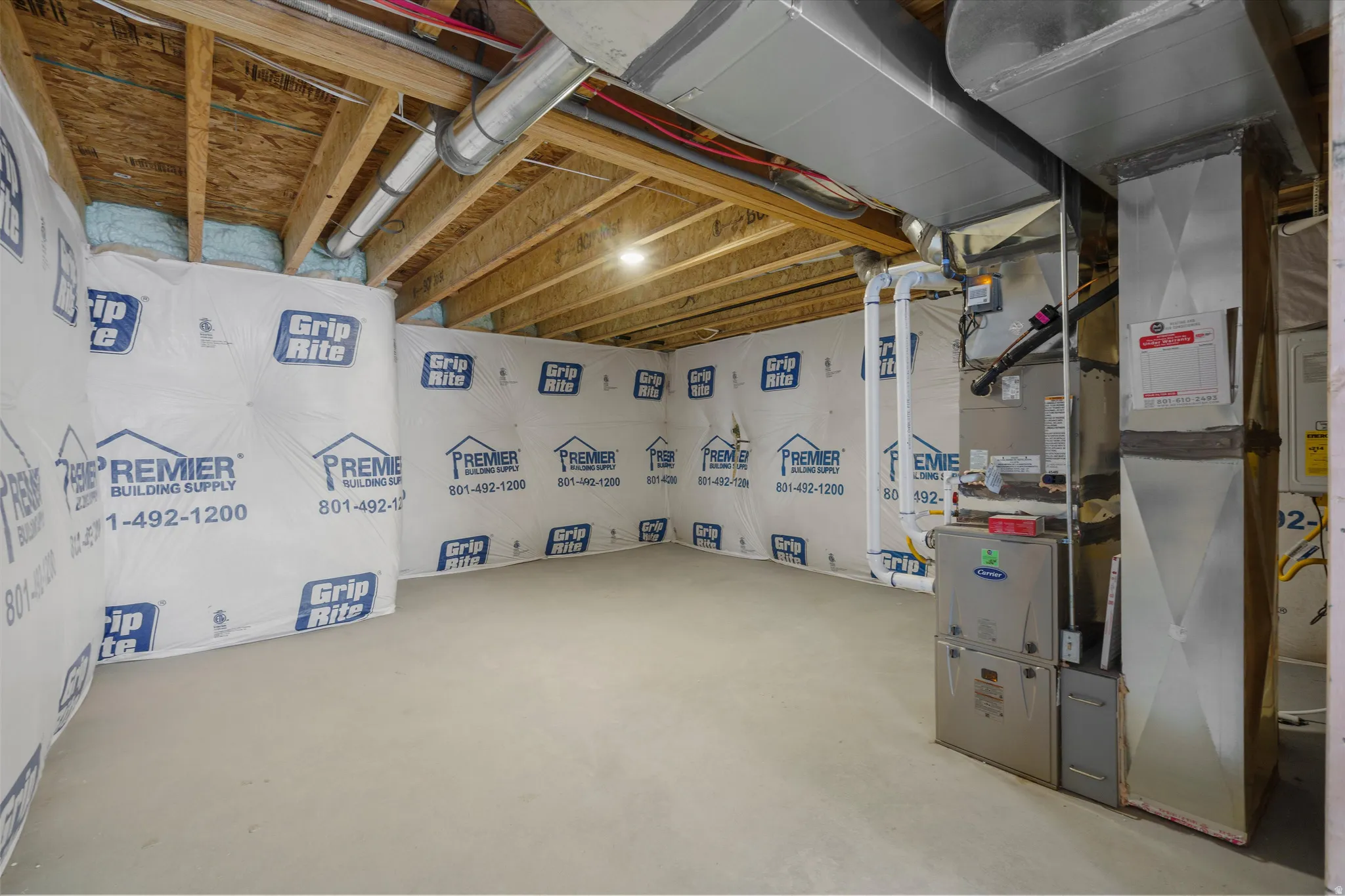 Unfinished basement with exposed ceiling joists, concrete flooring, and visible HVAC ductwork