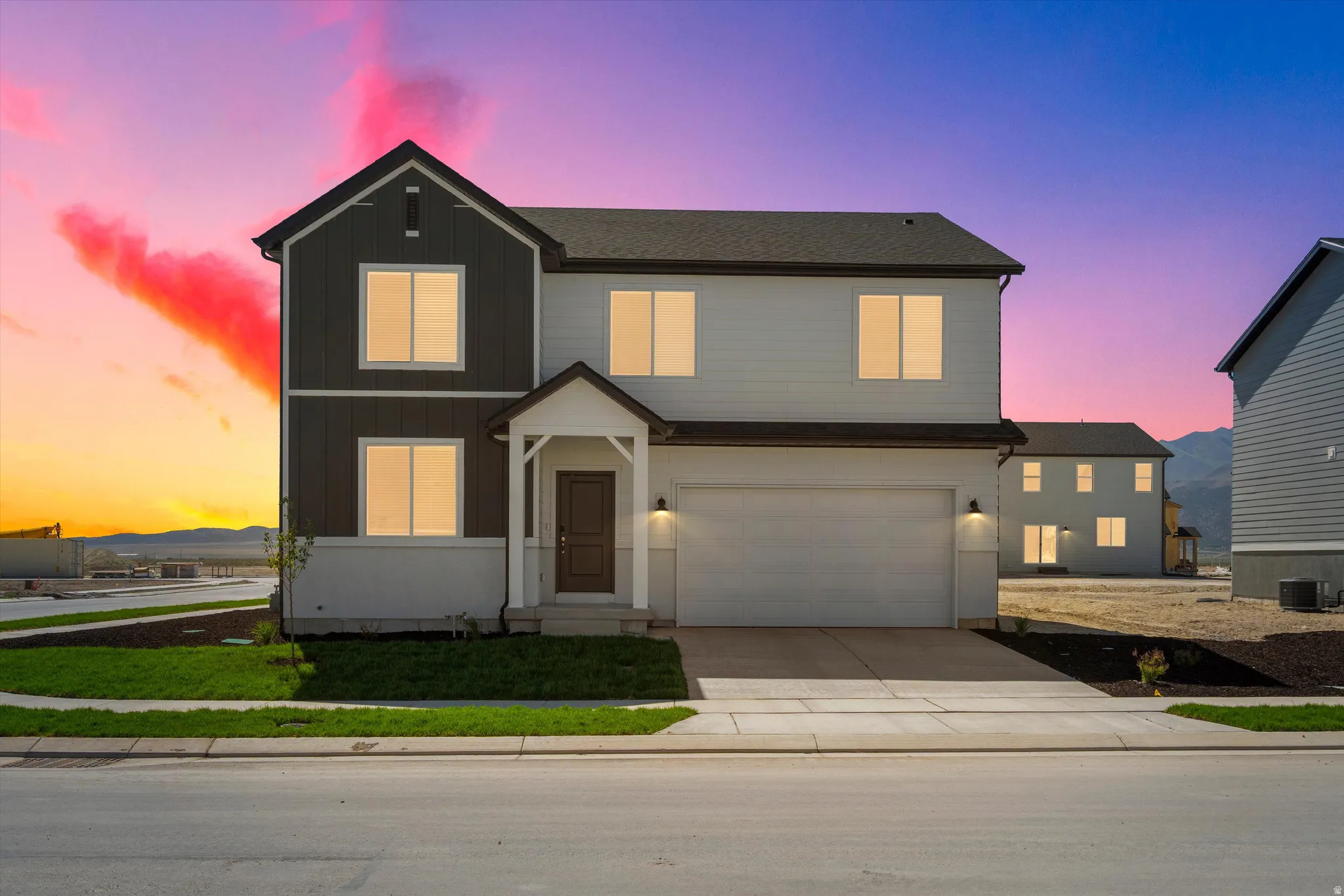 Two-story residence featuring a covered entry, attached garage, and a combination of horizontal siding and vertical paneling