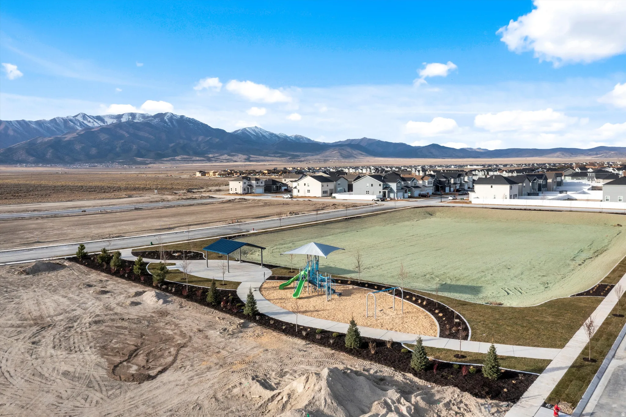 Community park featuring a playground, covered seating areas, and an expansive open green space