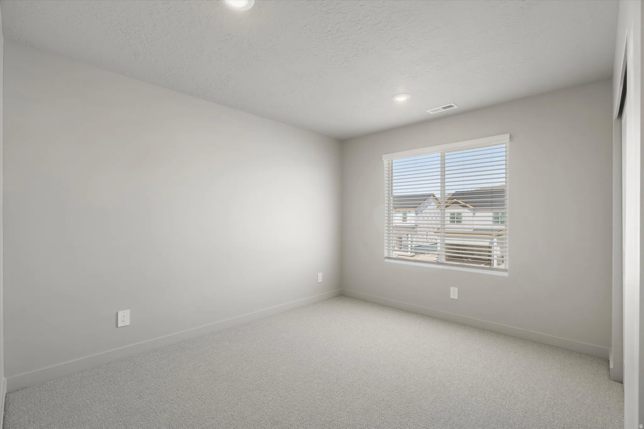 **DISCLAIMER** Interior package may vary. Recessed lighting, light gray wall paint, window with blinds, light gray carpet, and white trim