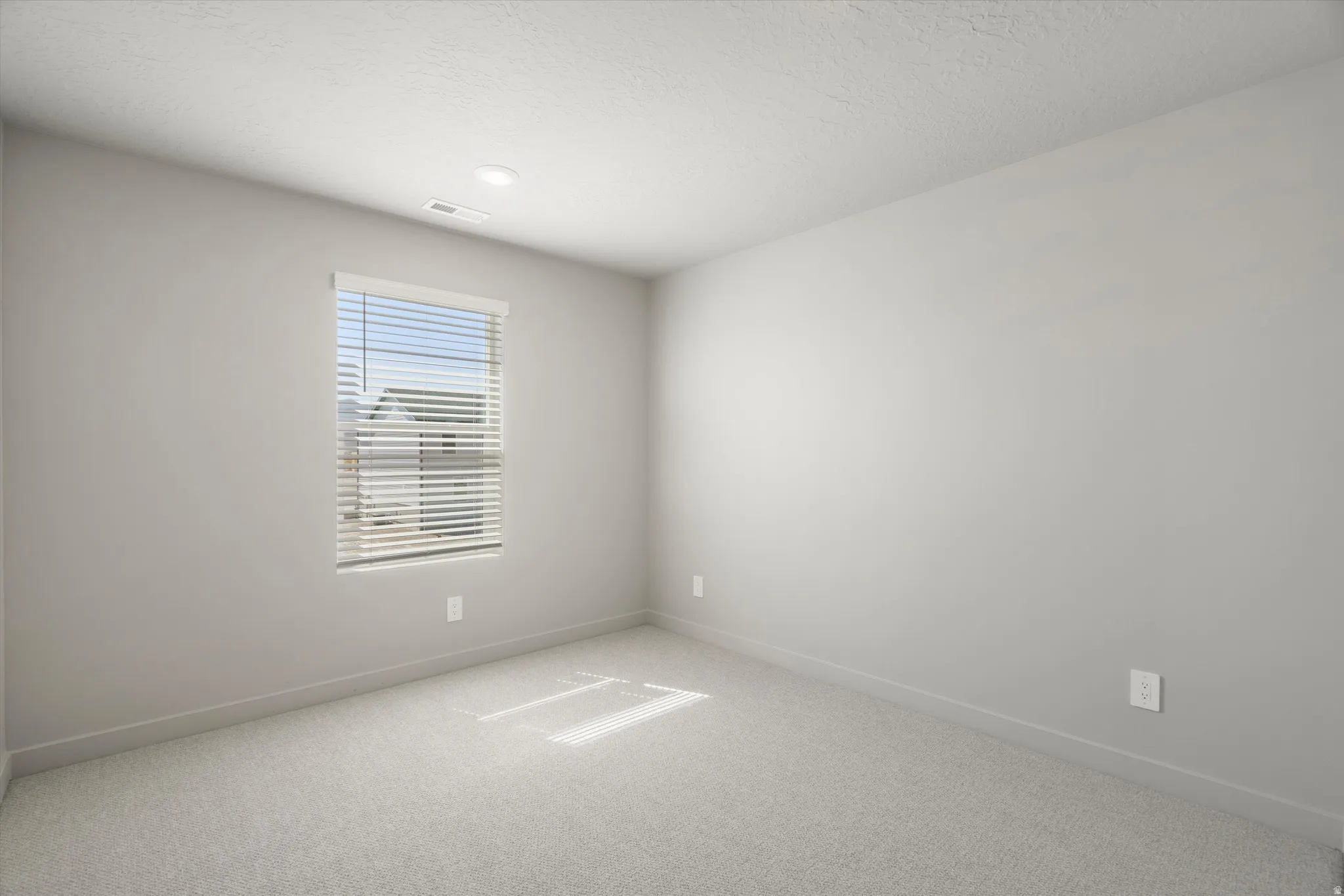 **DISCLAIMER** Interior package may vary. Recessed ceiling lighting, textured ceiling, light gray wall paint, carpeted flooring, window with blinds