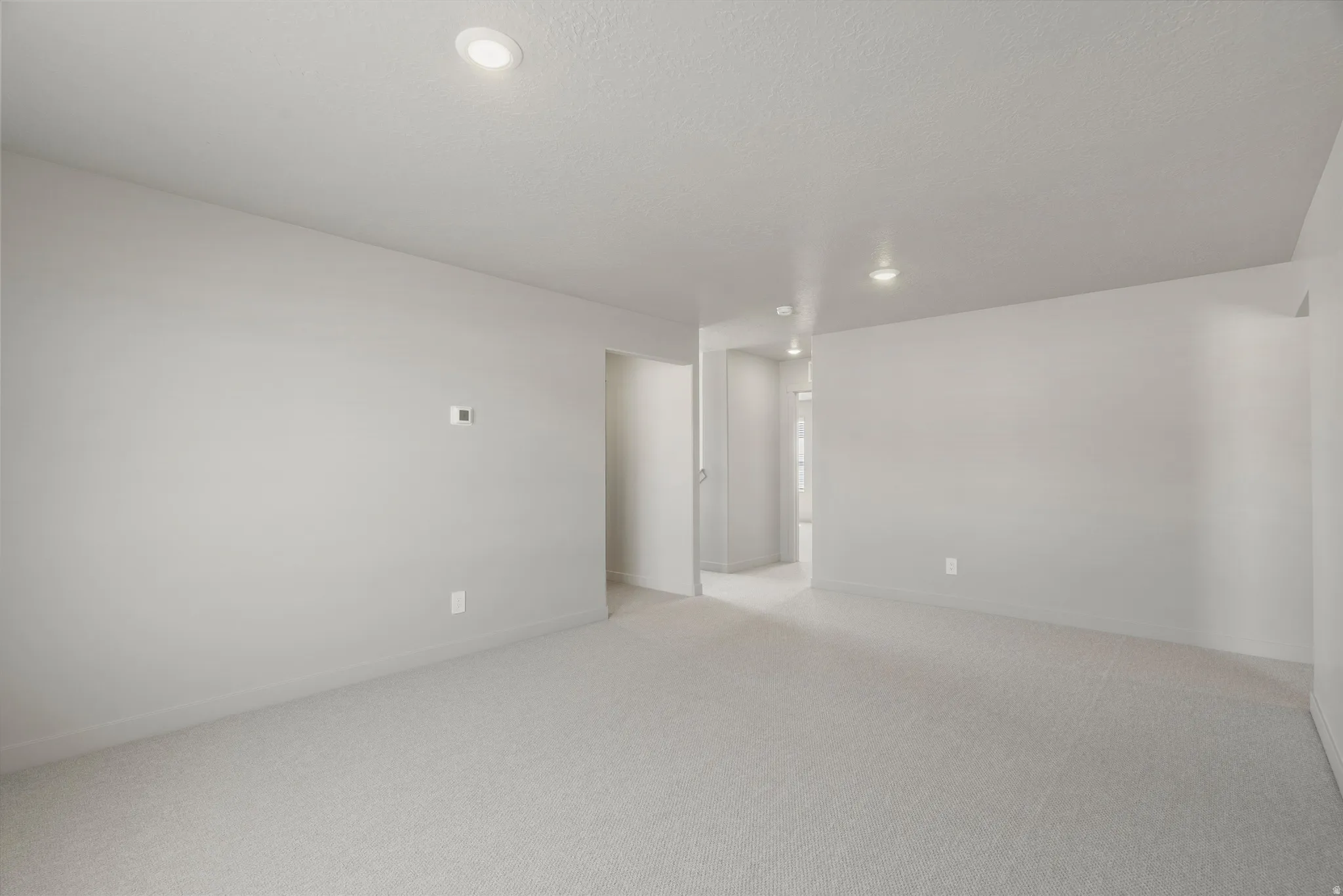 **DISCLAIMER** Interior package may vary. Spacious room featuring neutral wall finishes, recessed ceiling lighting, and neutral-toned carpet flooring