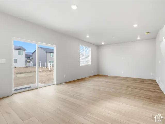 Open-concept interior featuring light wood-finish flooring, recessed lighting, and sliding glass patio doors