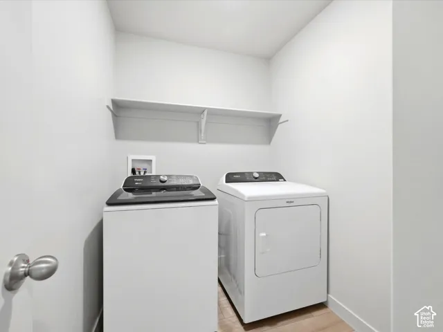 Laundry space featuring wood-finish flooring and a white wall-mounted shelf