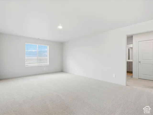 Neutral-toned carpeted flooring, white wall finishes, and a window with horizontal blinds
