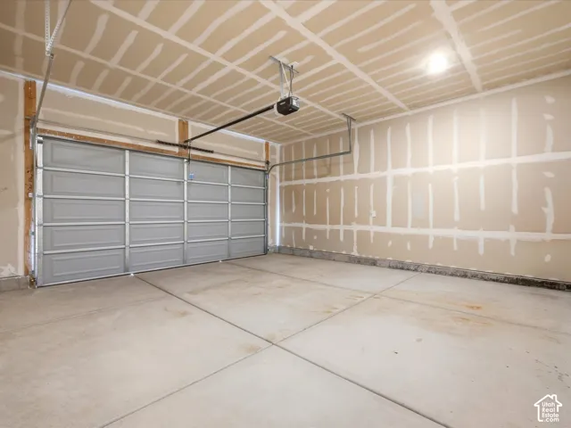 Multi-car garage featuring a concrete floor, sectional overhead door, and automated garage door opener